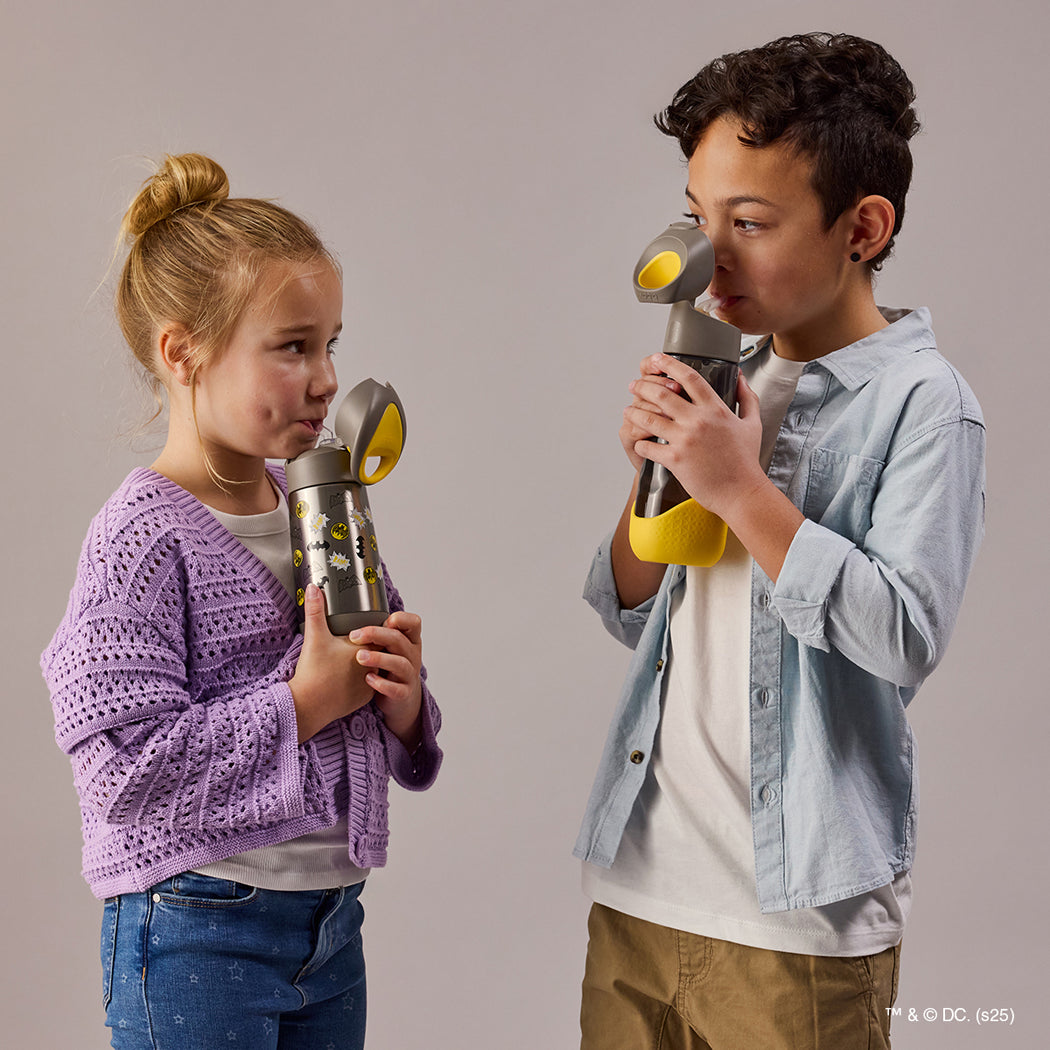 Two children holding toy gas masks against a plain background