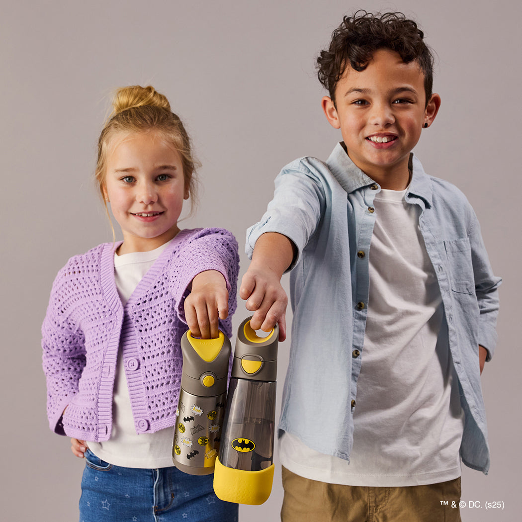 Two children holding a toy with Batman logo against a plain background