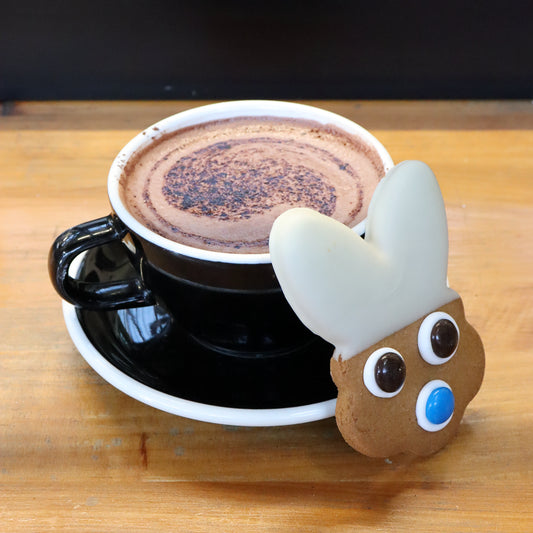 Cup of coffee with a cute animal-shaped object on a wooden surface