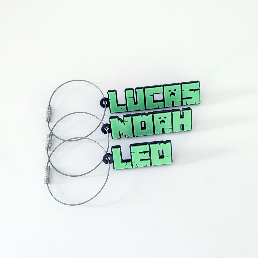 Three green name tag keychains with metal clips on a white background