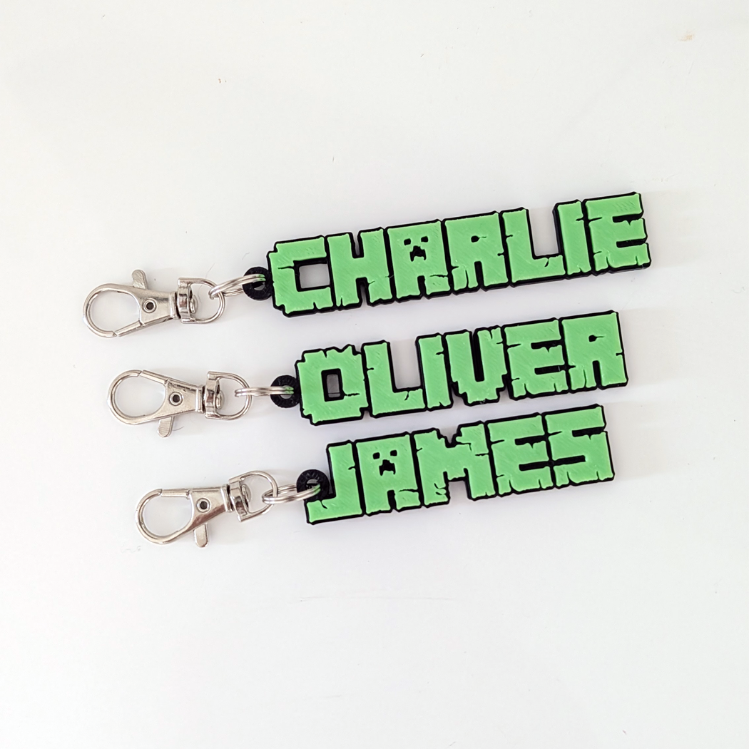 Three green name tag keychains with metal clips on a white background