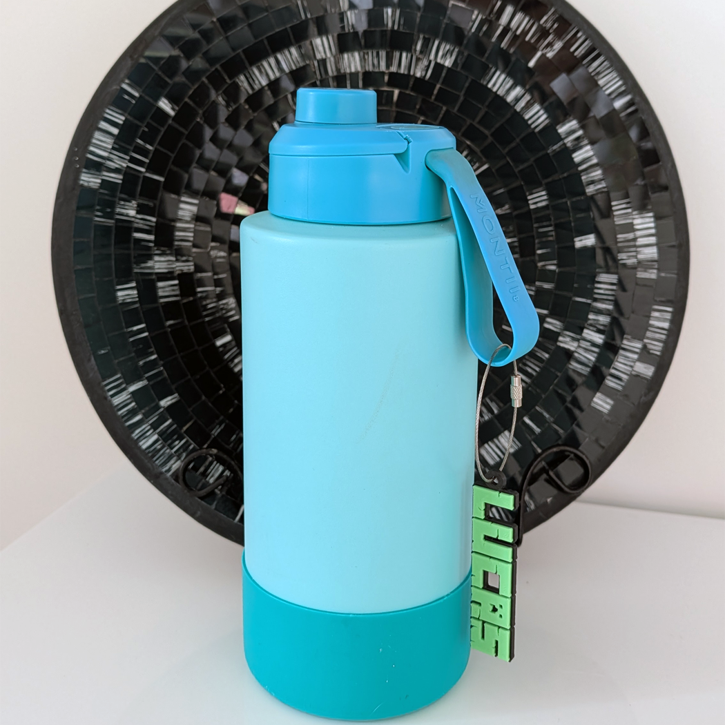 Blue water bottle with a handle on a white surface with a black mosaic background