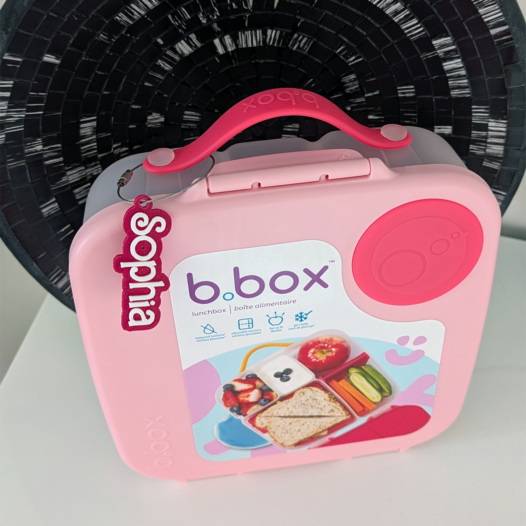 Pink b.box lunchbox with a fan in the background