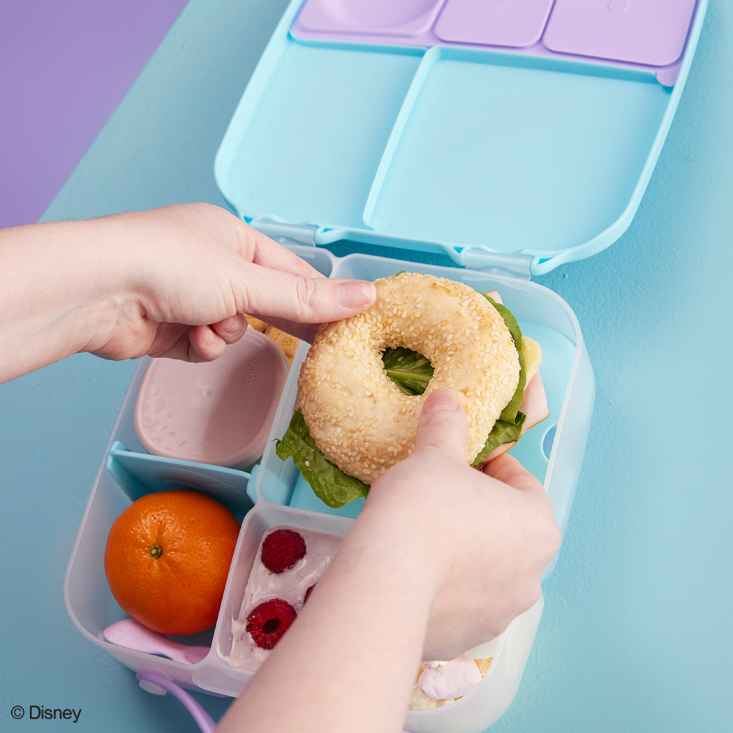 Bento box with a sandwich, fruit, and snacks on a colorful background