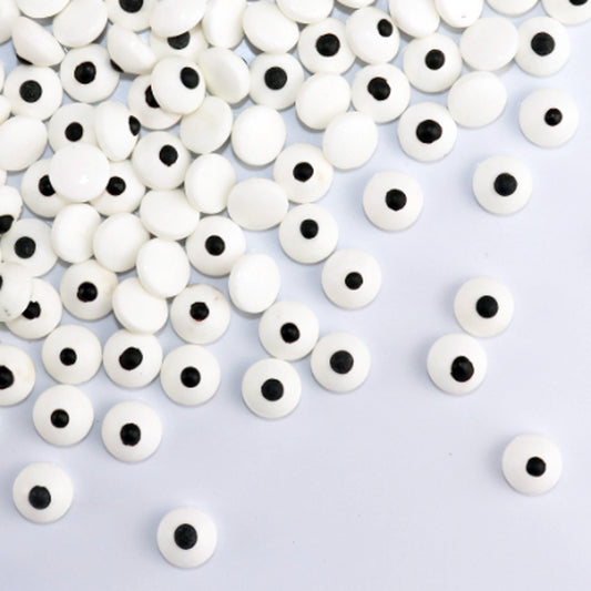White googly eyes with black centers scattered on a light gray background