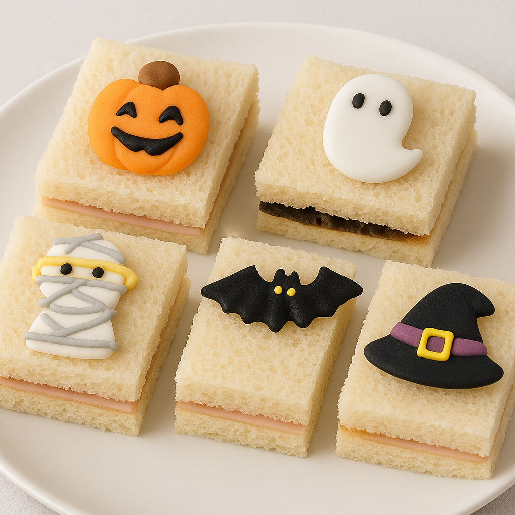 Halloween-themed sandwiches with decorative icing on a white plate.