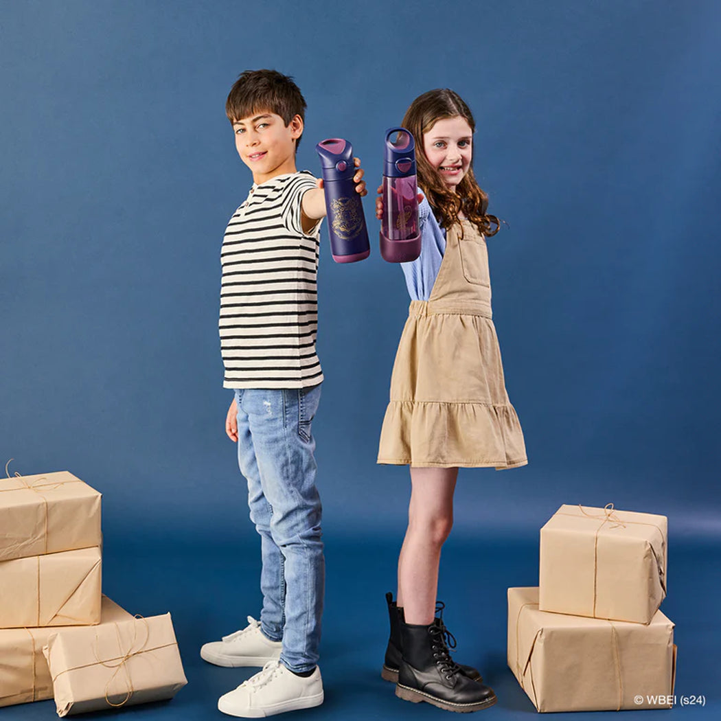 Two children holding purple bottles with cardboard boxes on a blue background