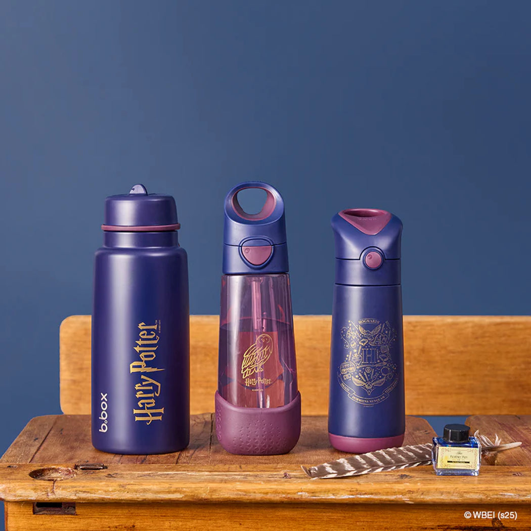Three Harry Potter-themed water bottles on a wooden surface with a blue background