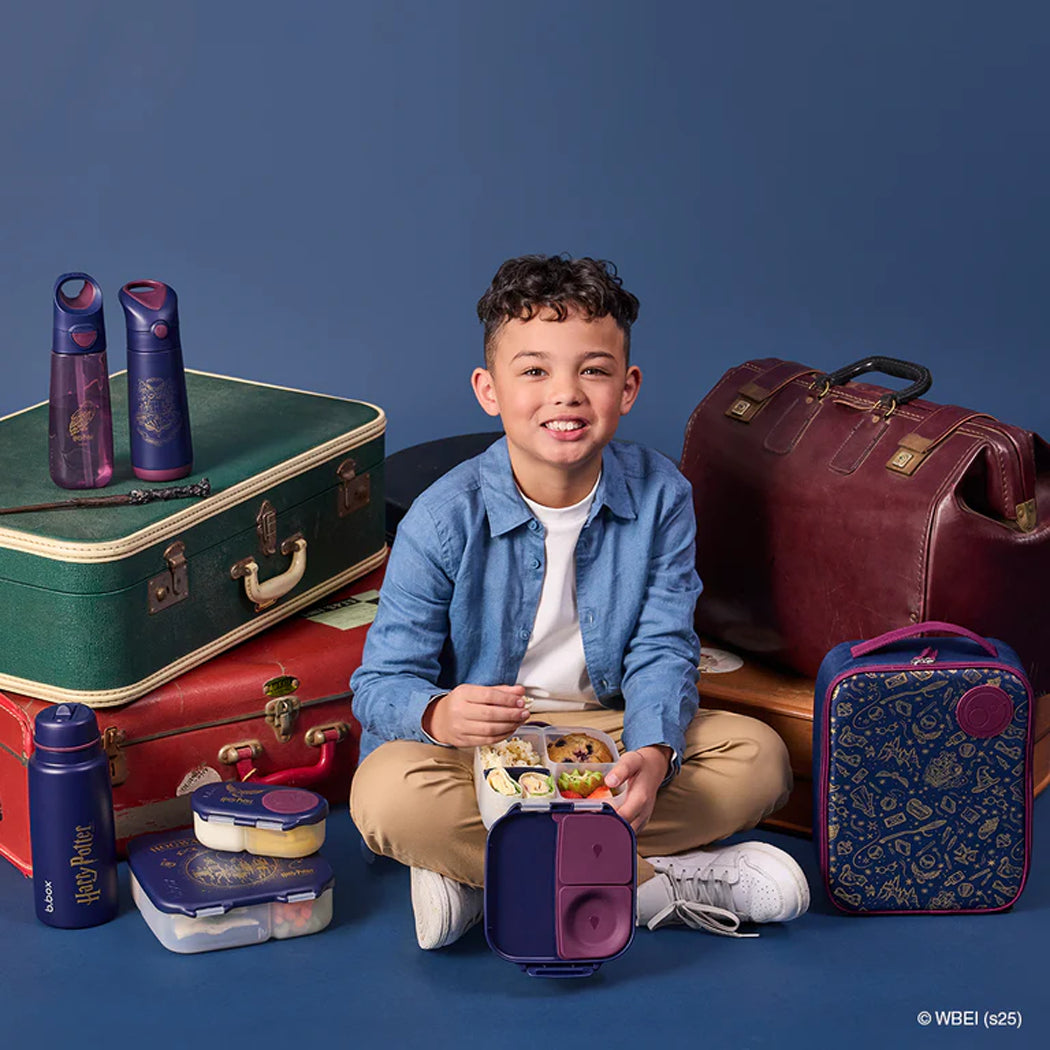 Child sitting with a lunchbox surrounded by various bags and containers on a blue background