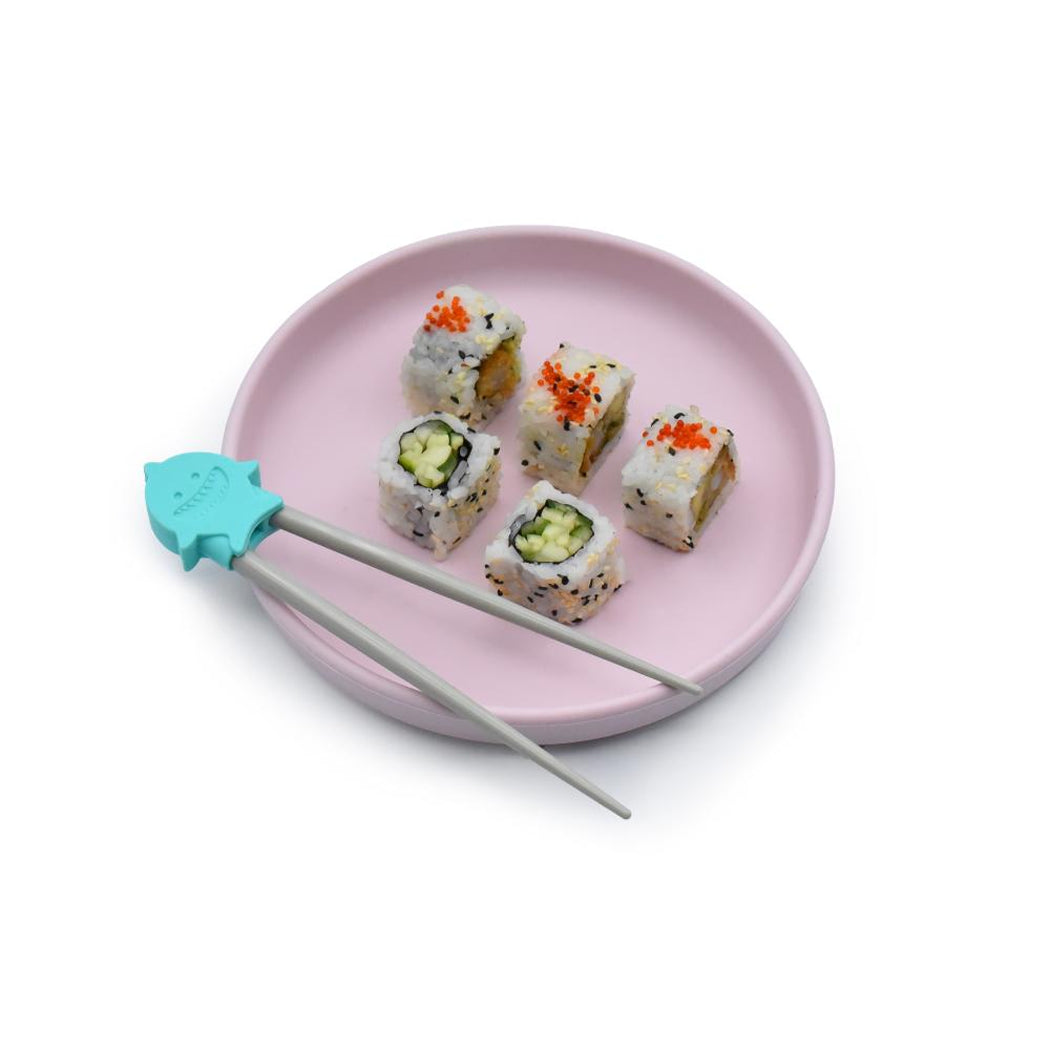 Sushi pieces on a pink plate with a pair of chopsticks featuring a turquoise holder.