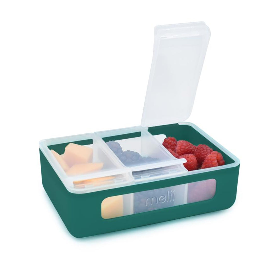 Green and white compartmentalized snack box with snacks and berries on a white background