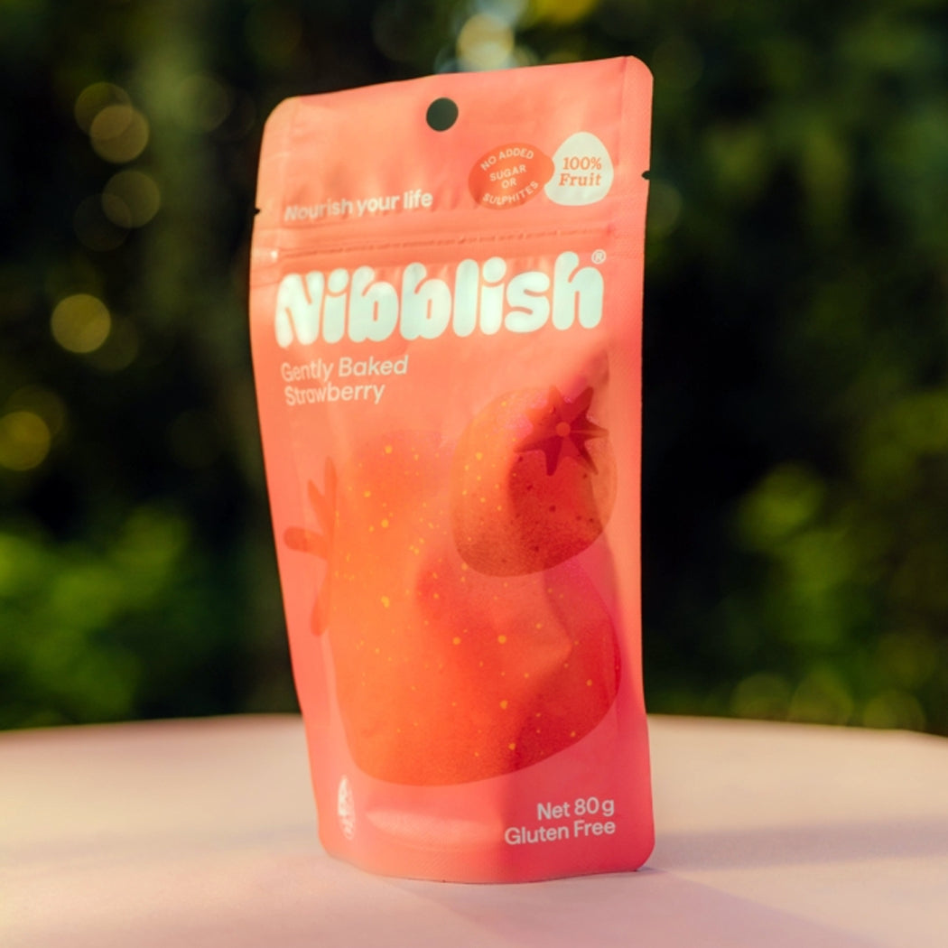 Nibblish strawberry snack package on a blurred green background