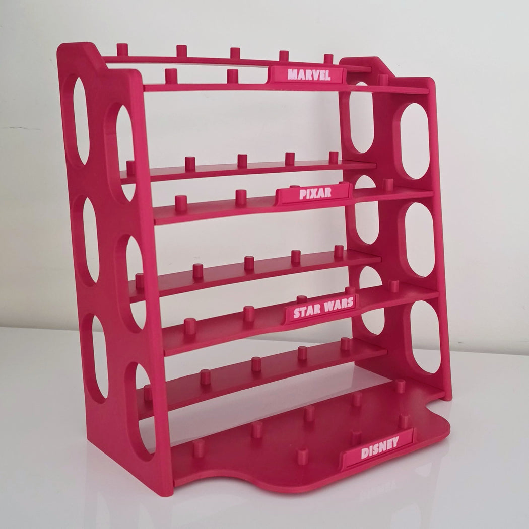 A bright pink plastic toy or collectible display rack with five shelves and circular cutouts, featuring printed brand labels for Marvel, Pixar, Star Wars, and Disney on the front.