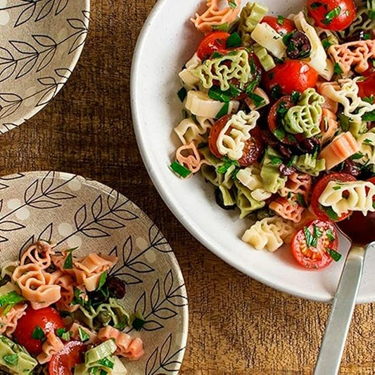 Colorful pasta salad on a white plate with a wooden background