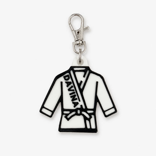 A white and black rubber charm shaped like a martial arts gi robe with the name 'DAVINA' printed on the chest, attached to a silver lobster clasp, shown on a light gray background.