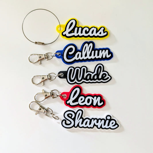 Five keychains with names printed on them against a white background