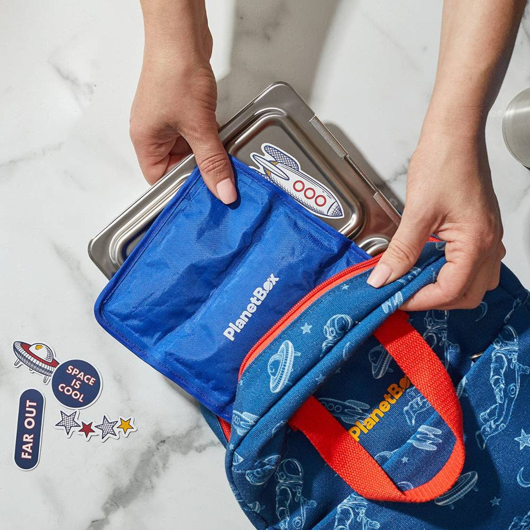 Person opening a blue PlanetBox lunch bag on a marble surface