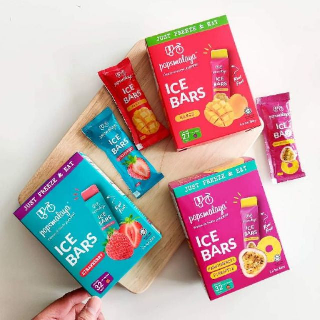 Popsomalaya ice bar packages on a wooden board with a hand holding one package.