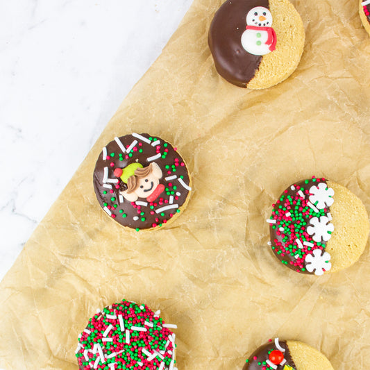 Decorative cookies with chocolate icing and sprinkles on a sheet of brown paper.