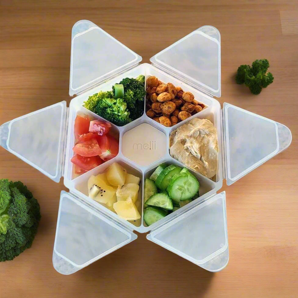 Transparent food container with compartments filled with various foods on a granite countertop