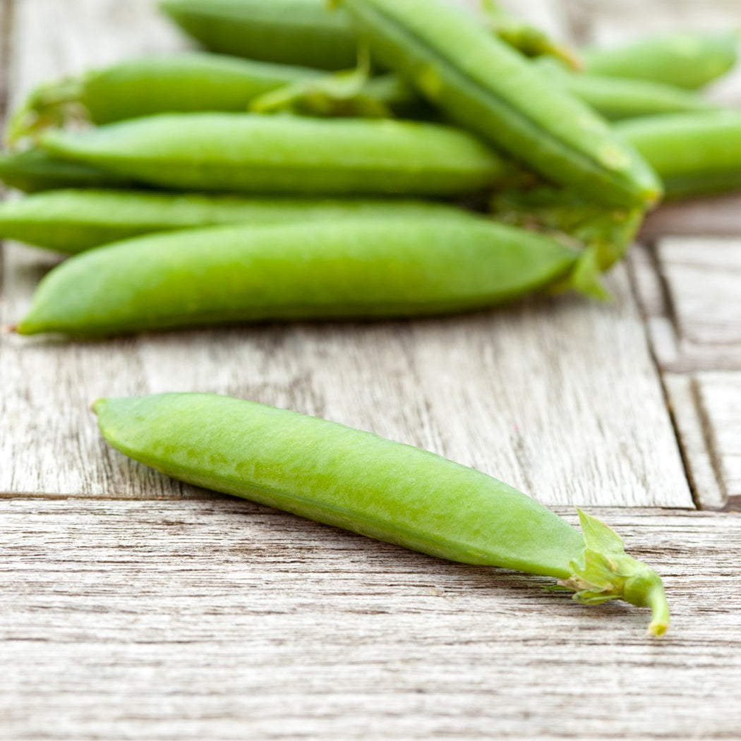 Green peas in pods on a wooden surface