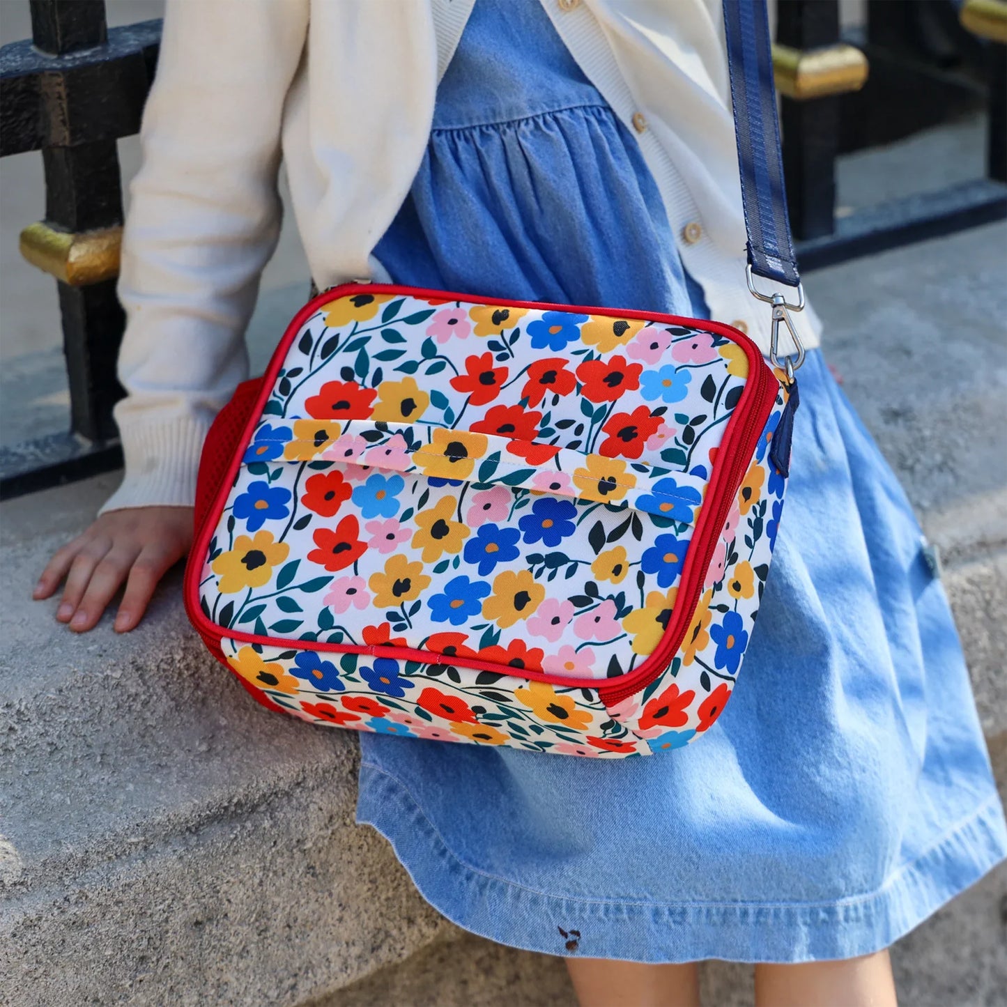Person wearing a colorful floral-patterned bag outdoors.