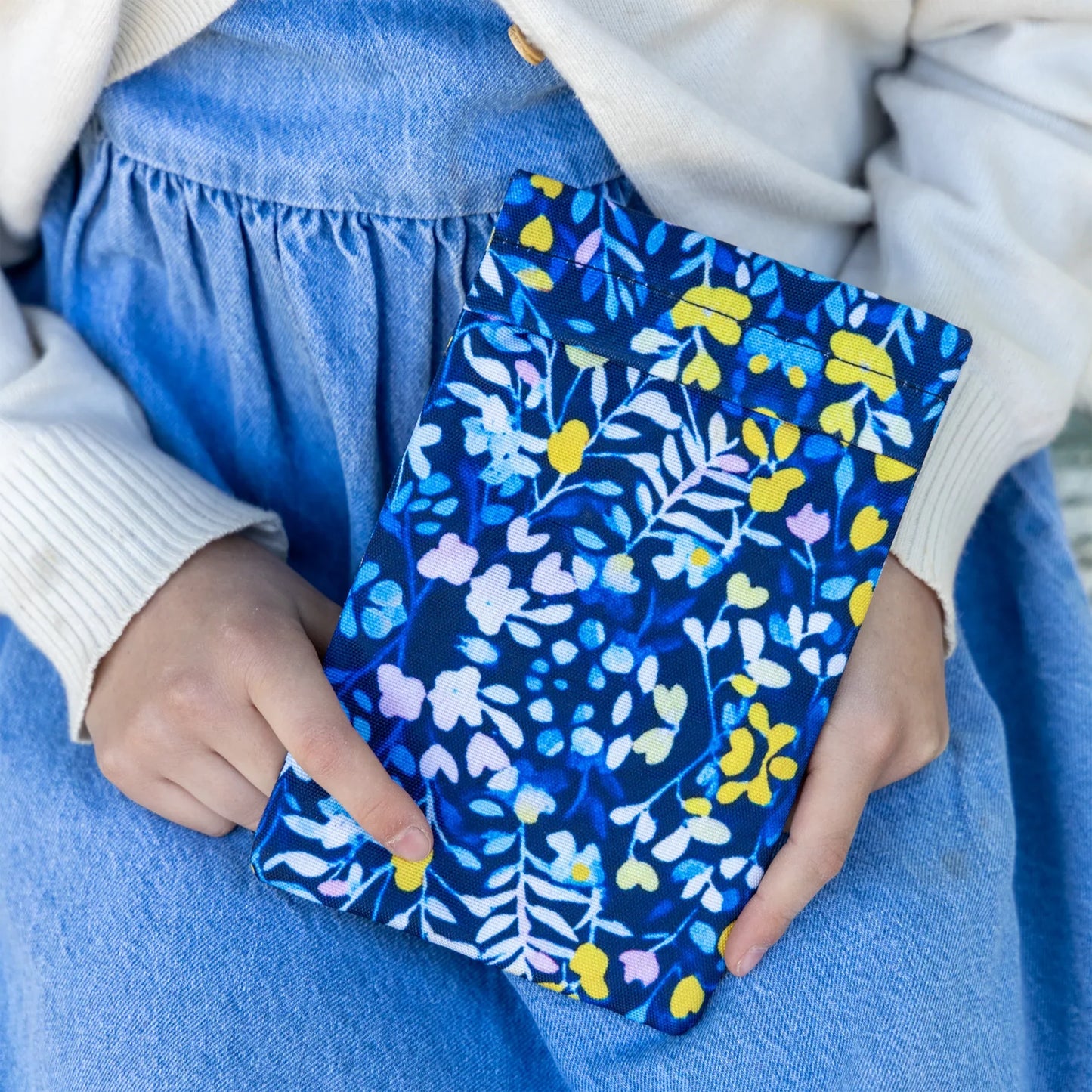 Person holding a blue floral-patterned pouch