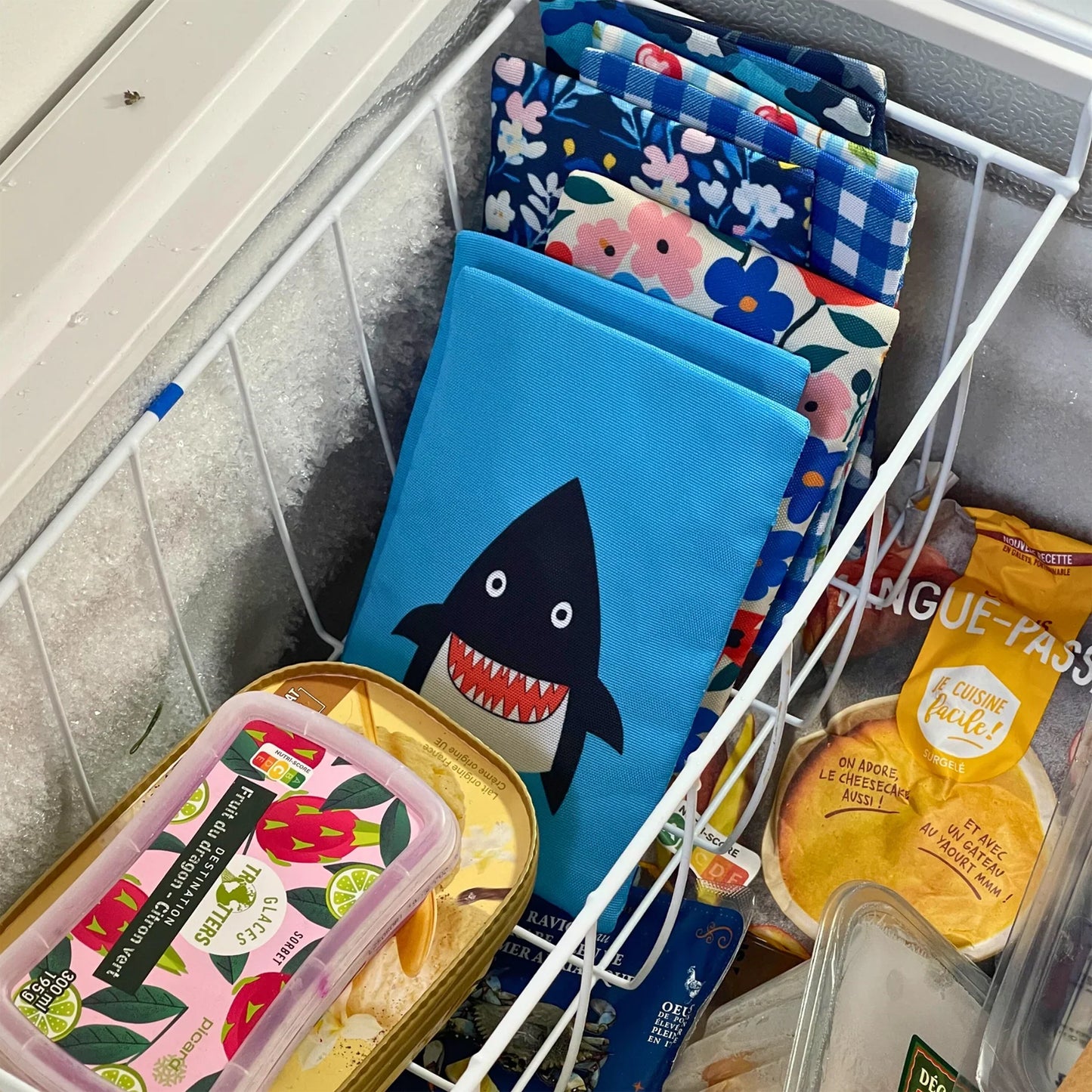 Assorted reusable bags with different designs in a shopping cart.