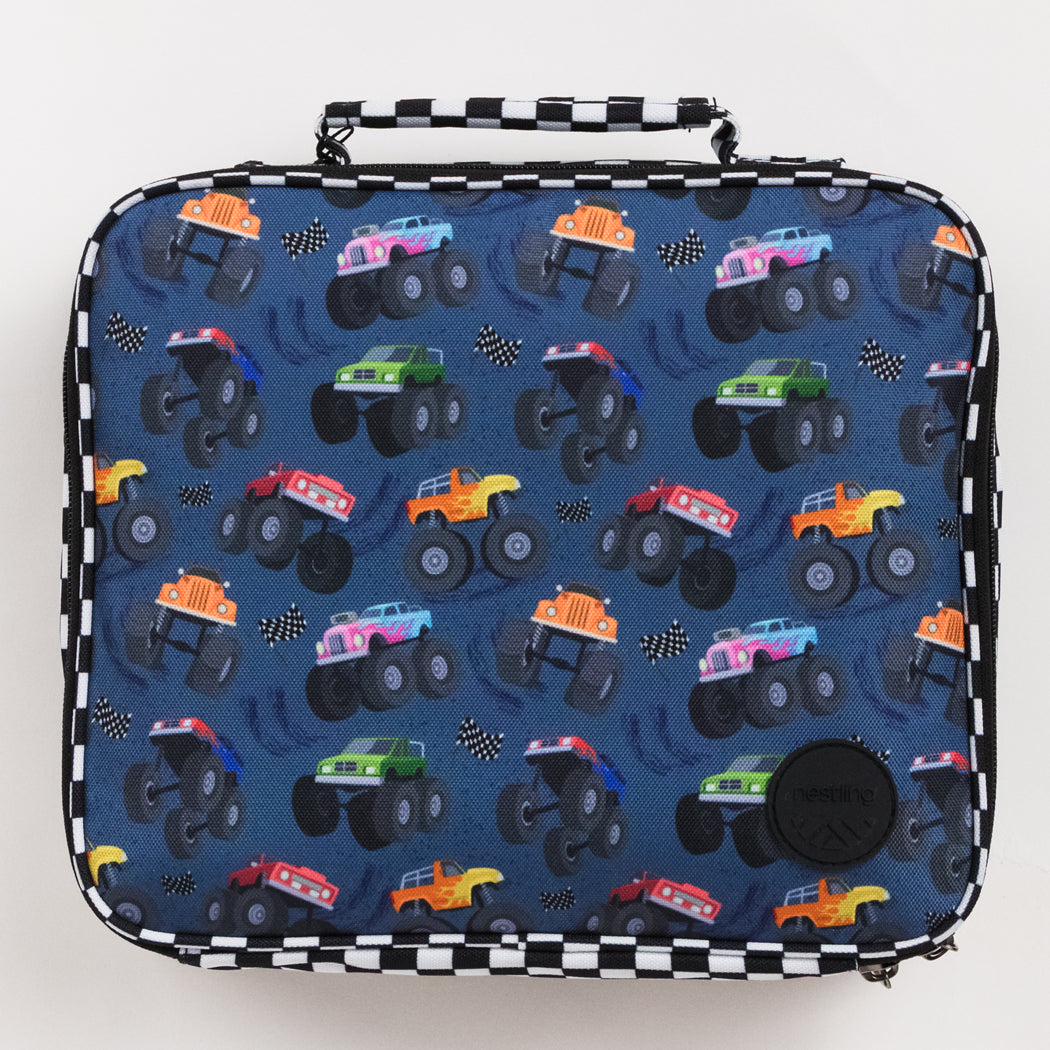 A square lunch bag with a black and white checkered handle and trim, featuring a blue patterned front with cartoon monster trucks and small black-and-white checkered flags.