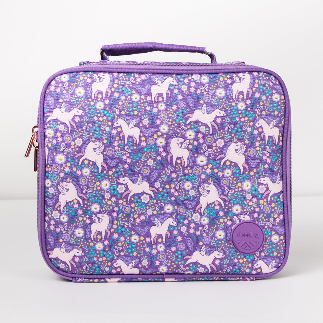 A purple lunch bag with a floral unicorn pattern, featuring a top handle, zippered closure, and a circular brand patch on the front.