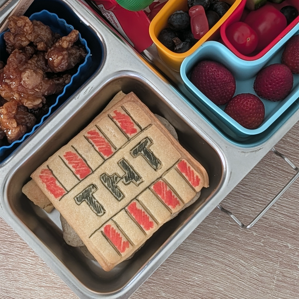 Lunchbox with a TNT cookie and fruit compartments