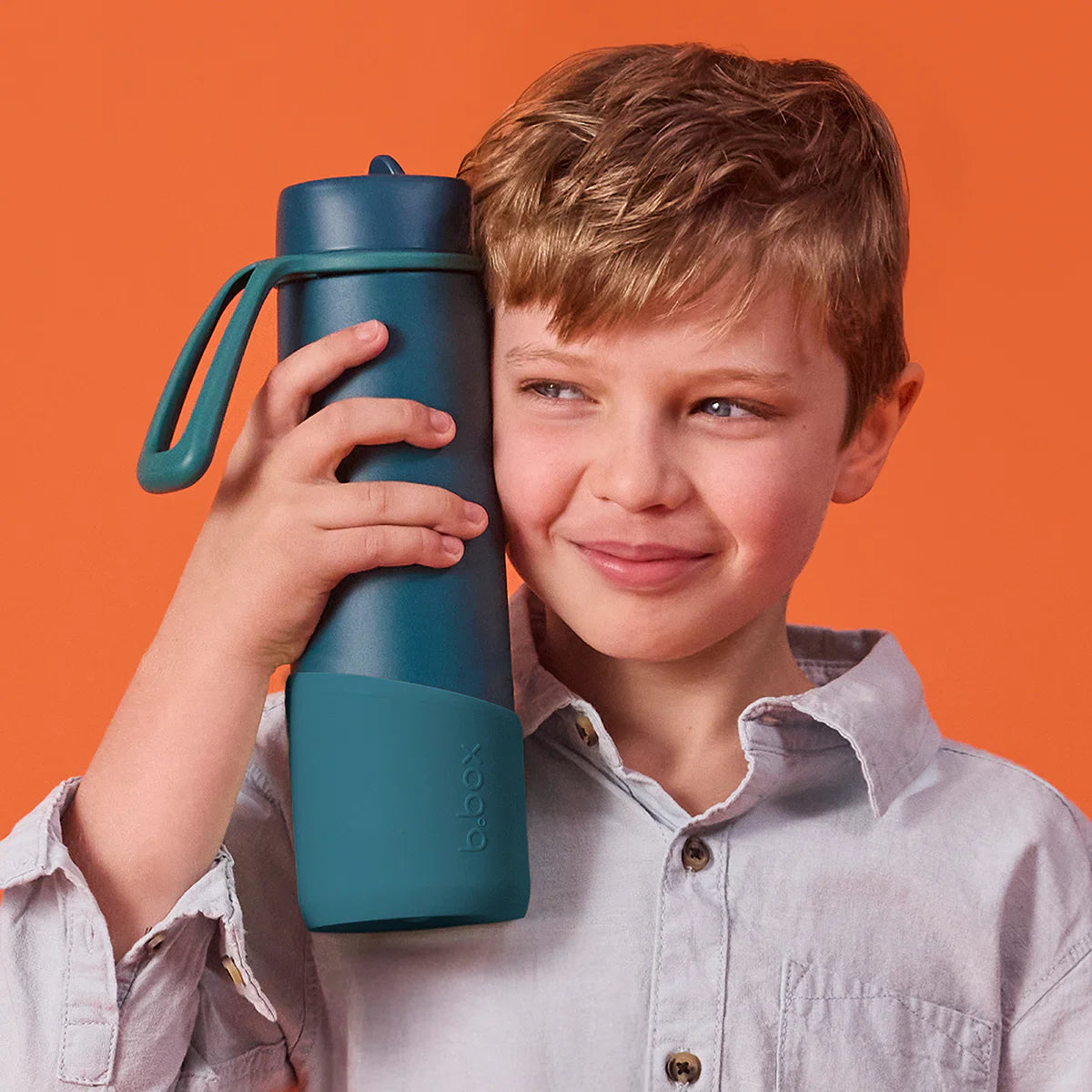 Child holding a blue water bottle with a brand logo against an orange background
