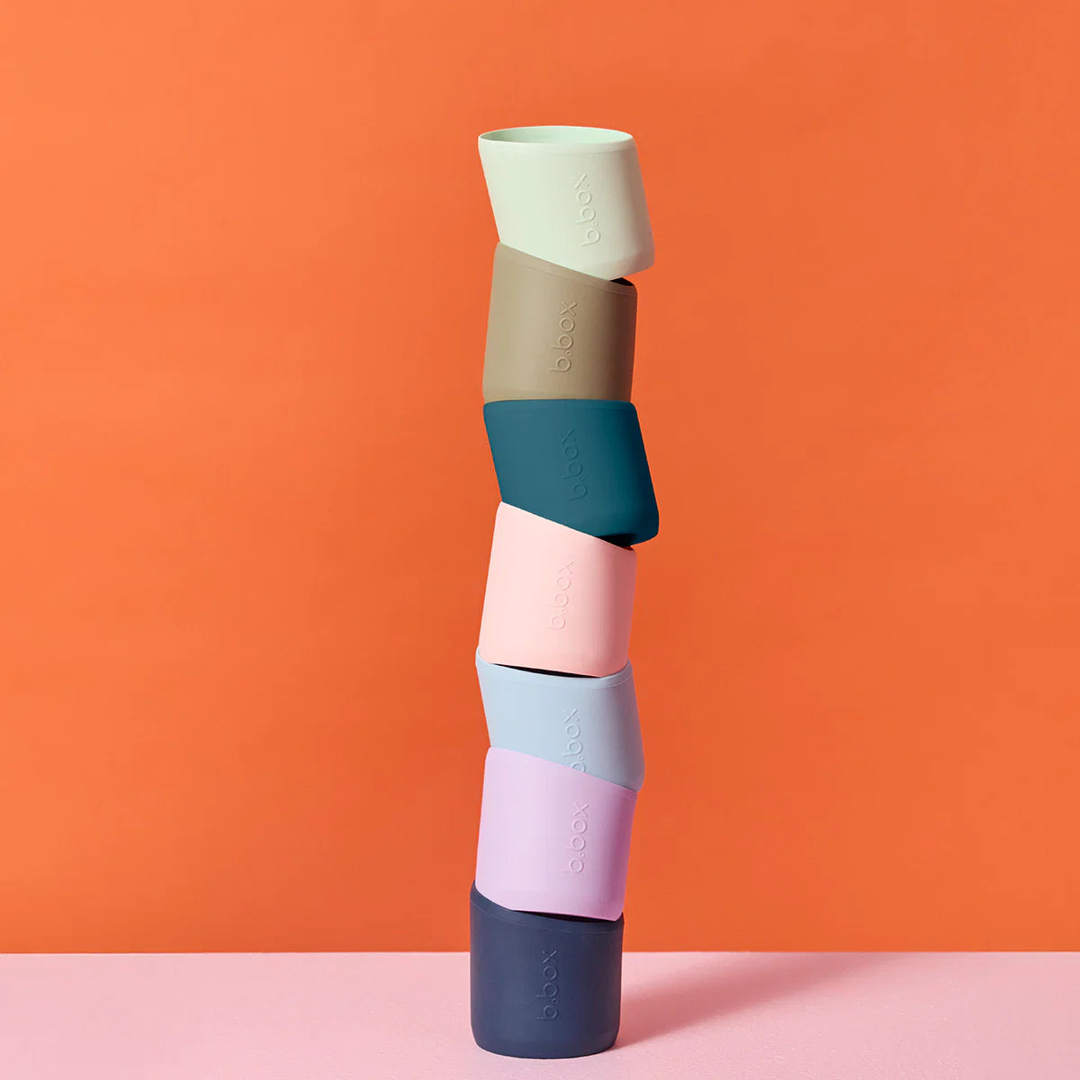 Stack of colorful silicone cups on an orange background