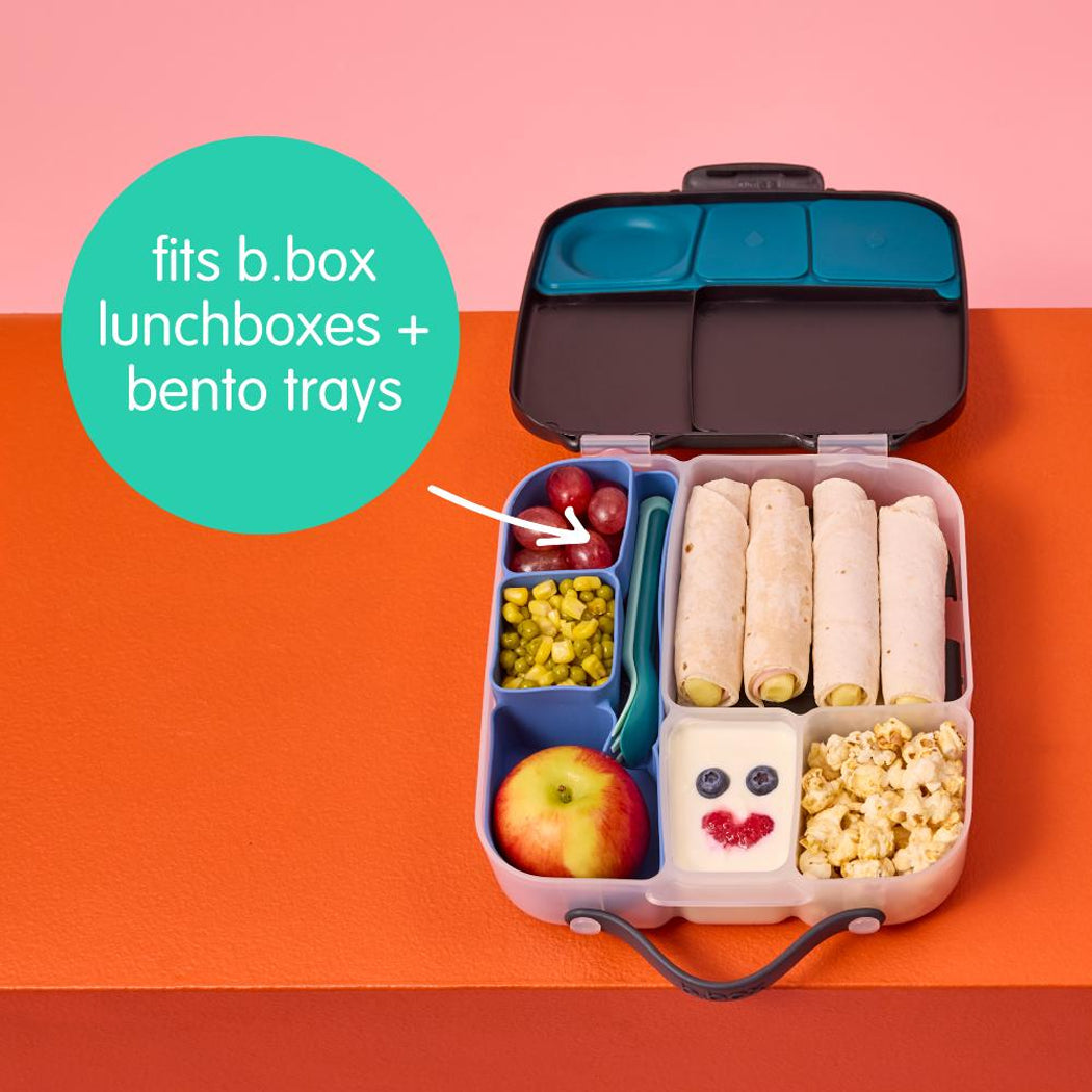 Bento box with compartments filled with food on a pink and orange background