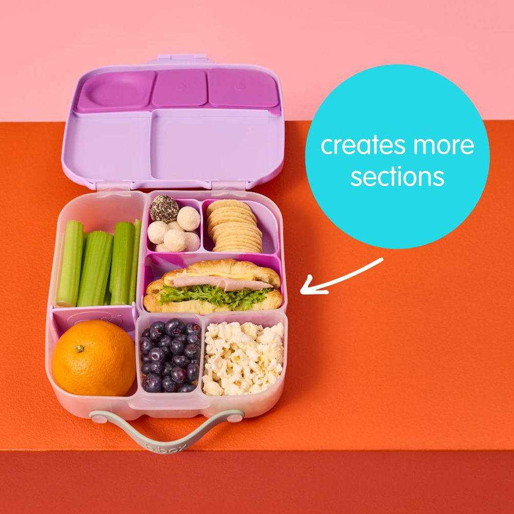 Pink bento box with compartments filled with food on a pink and orange background