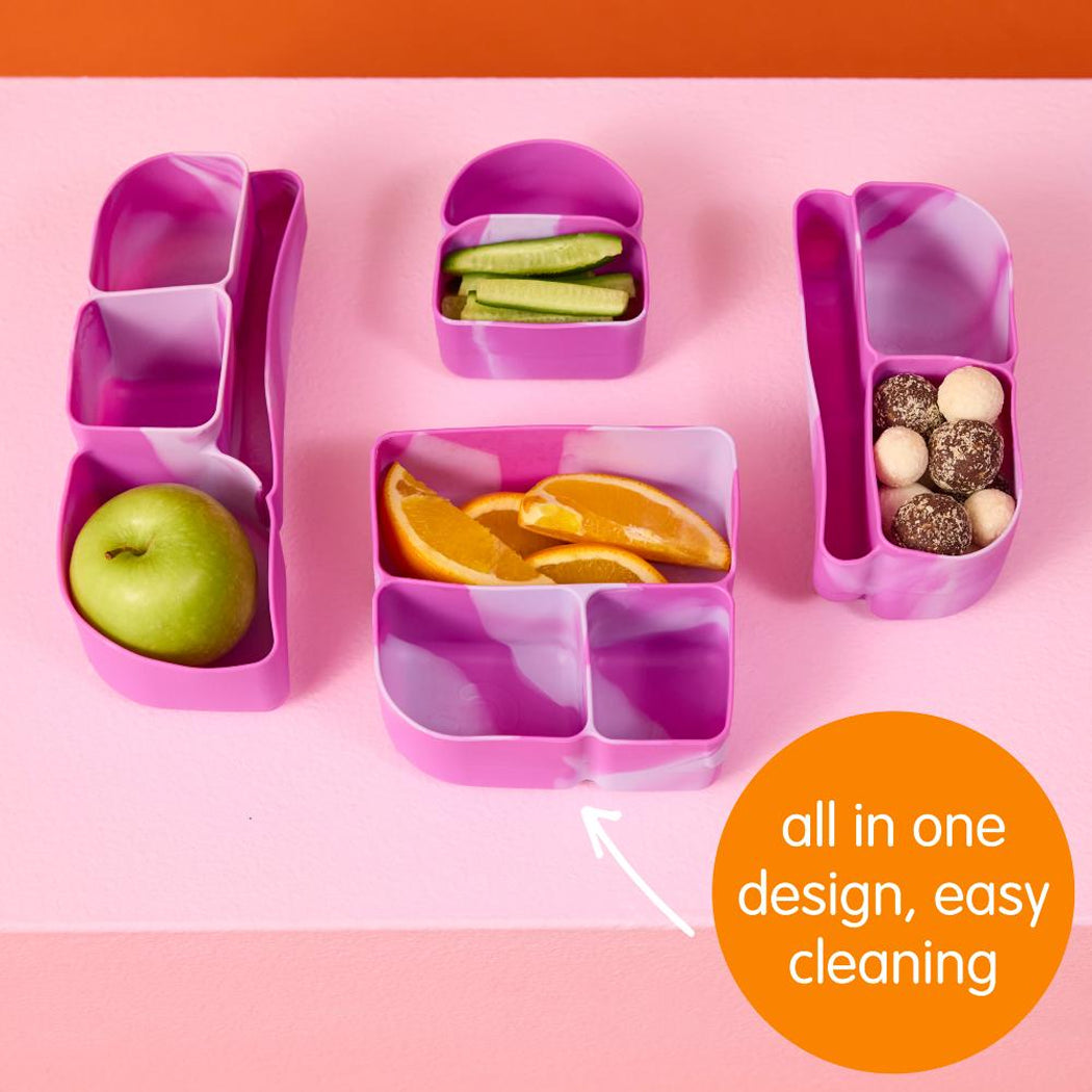 Set of purple bento boxes with compartments containing fruits and snacks on a pink background.