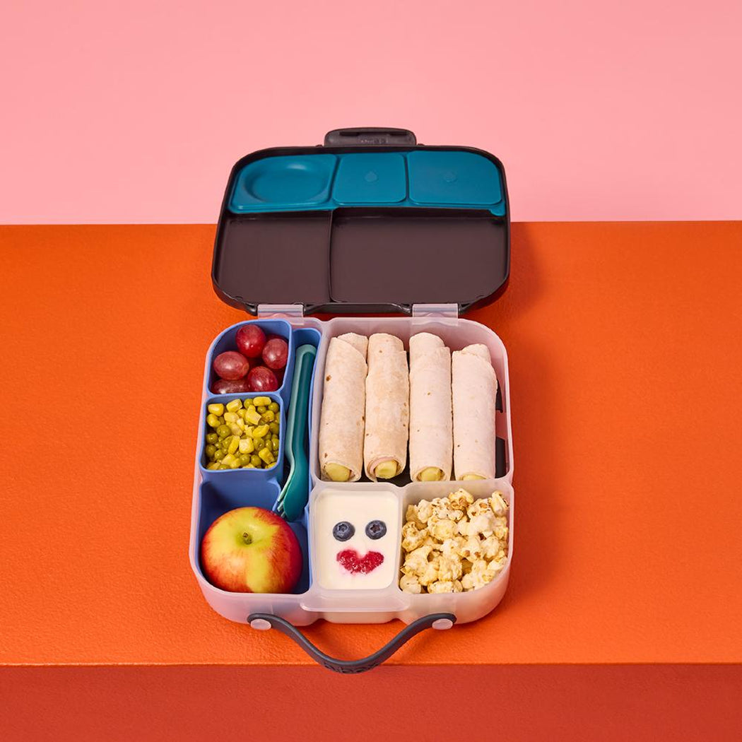 Lunchbox with various food items on a two-tone background