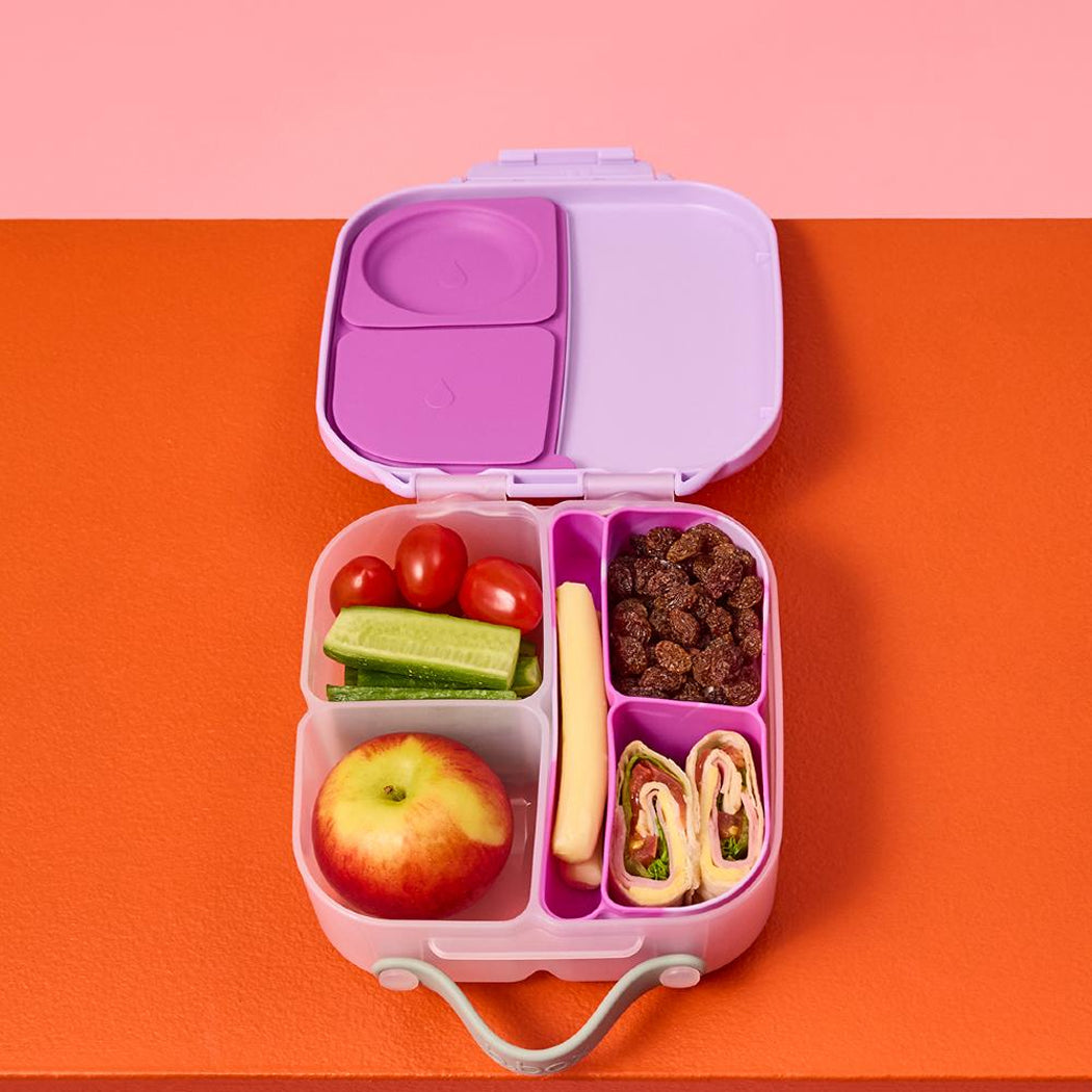 Pink bento box with compartments filled with food on a pink and orange background