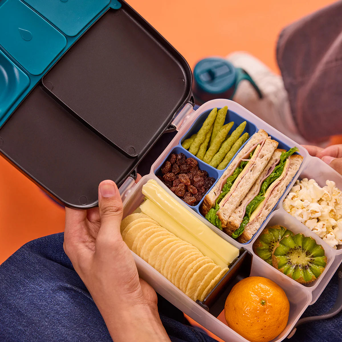 Lunchbox with compartments filled with various food items on an orange background