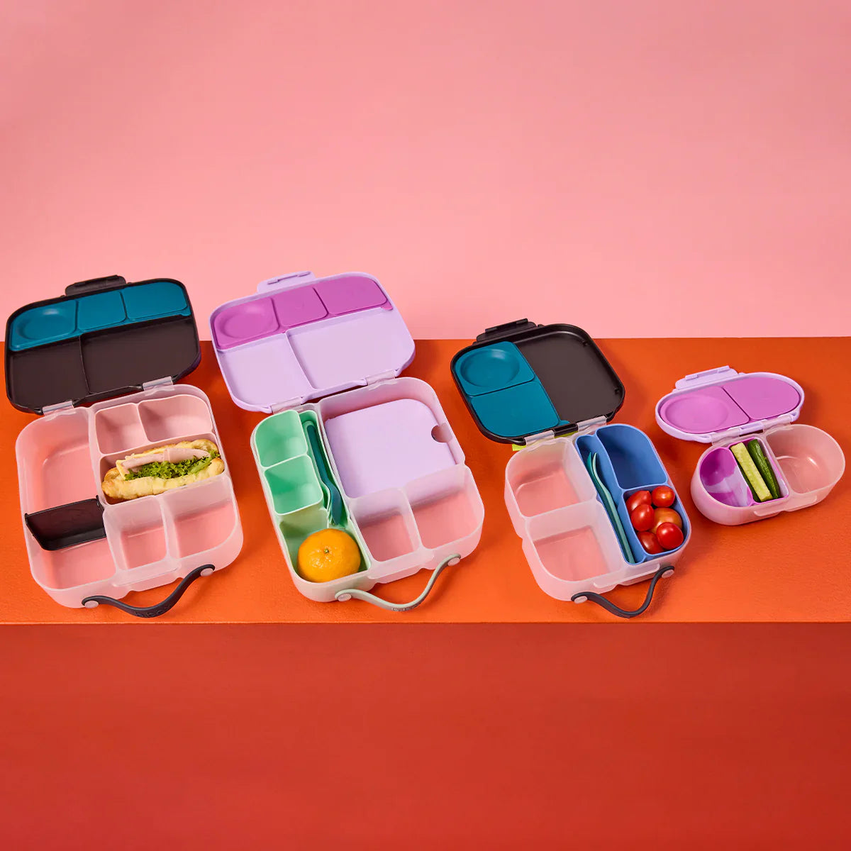 Colorful bento boxes with compartments on a pink and orange background