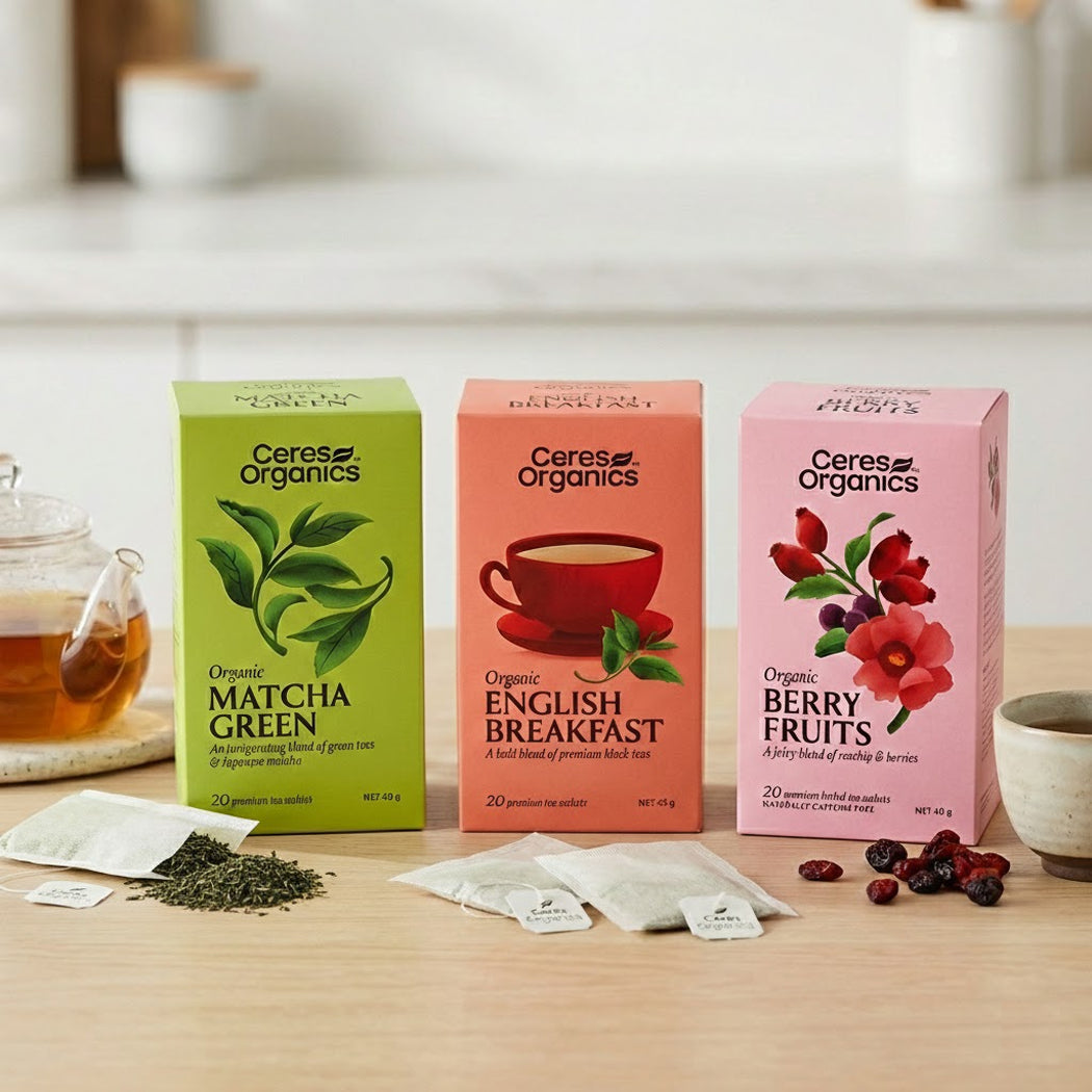 Three boxes of Ceres Organics tea on a wooden table with tea bags and ingredients.