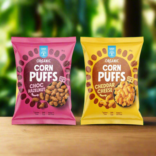 Two packages of organic corn puffs, one pink and one yellow, on a white background.