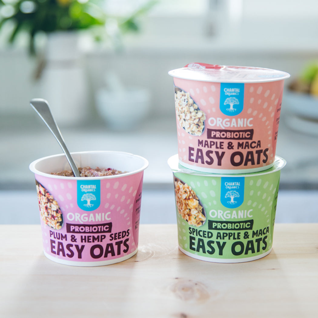 Three containers of Organic Probiotic Easy Oats with different flavors on a table.