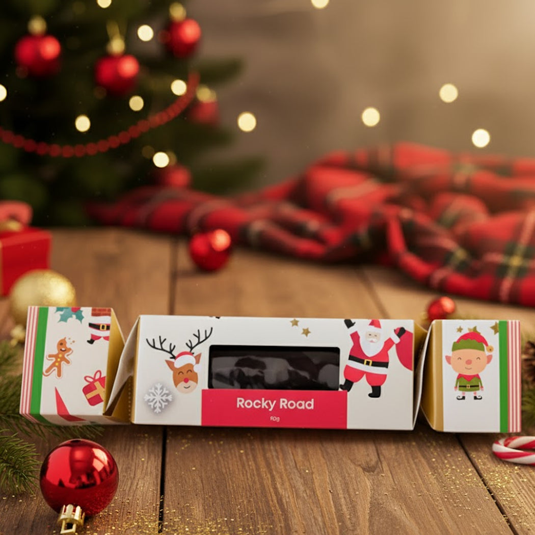 Christmas-themed Rocky Road packaging with festive illustrations on a wooden surface.