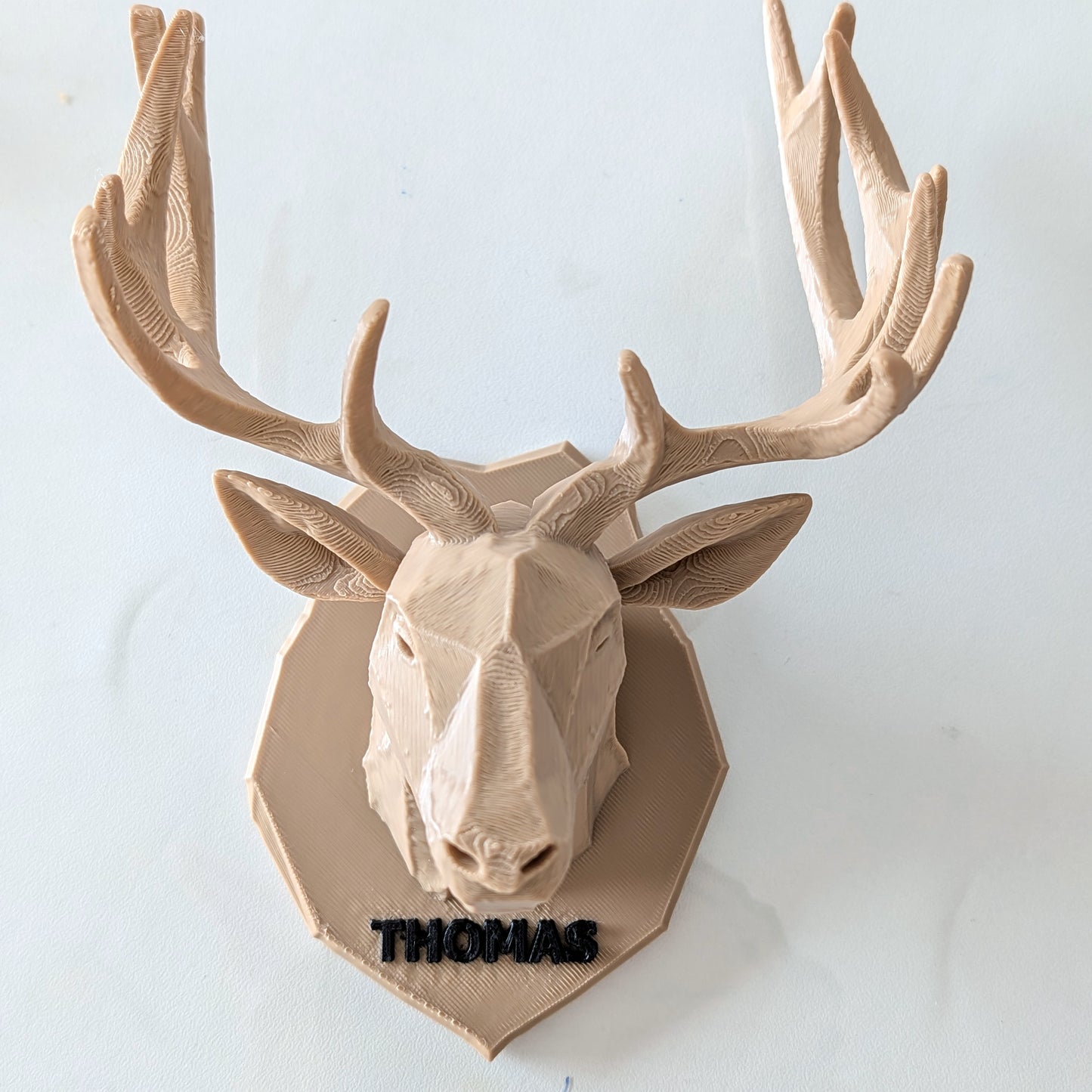 A 3D-printed custom deer head wall mount with antlers, personalized with the name 'THOMAS' in black embroidery on the base, shown against a plain light background.