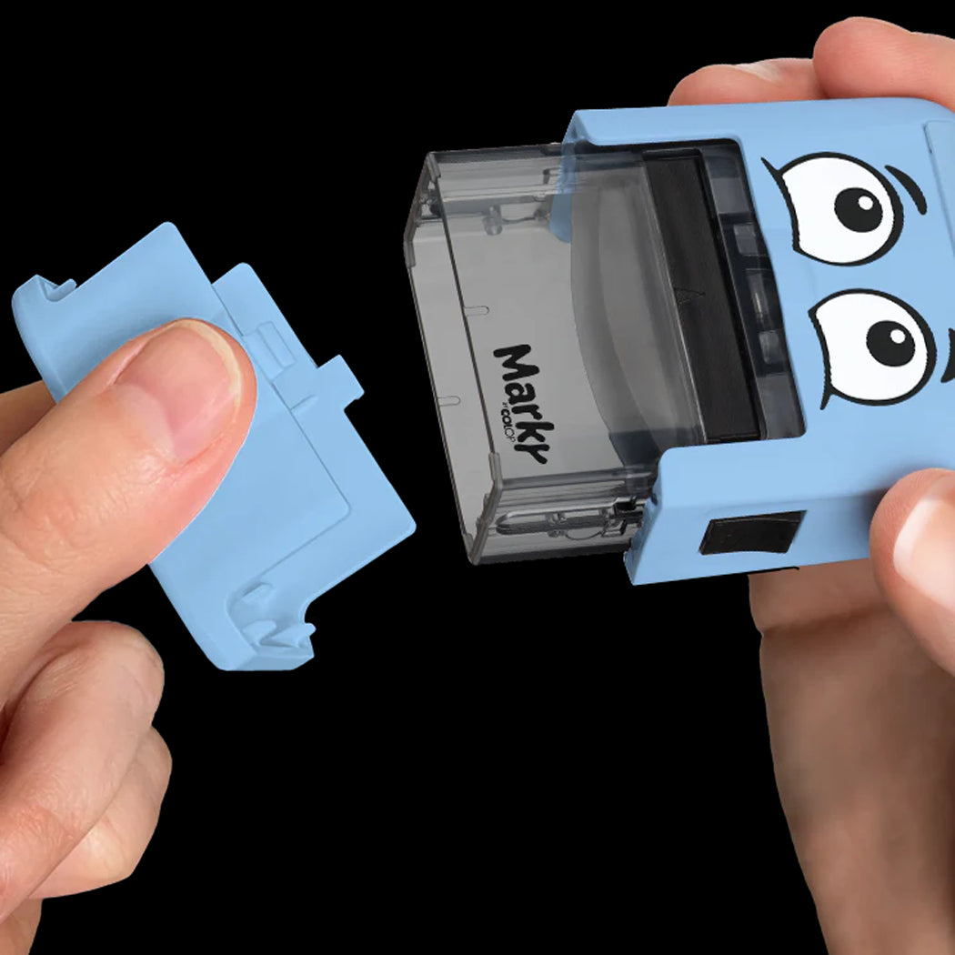 Blue Markr product with cartoon face design held by hands against a black background