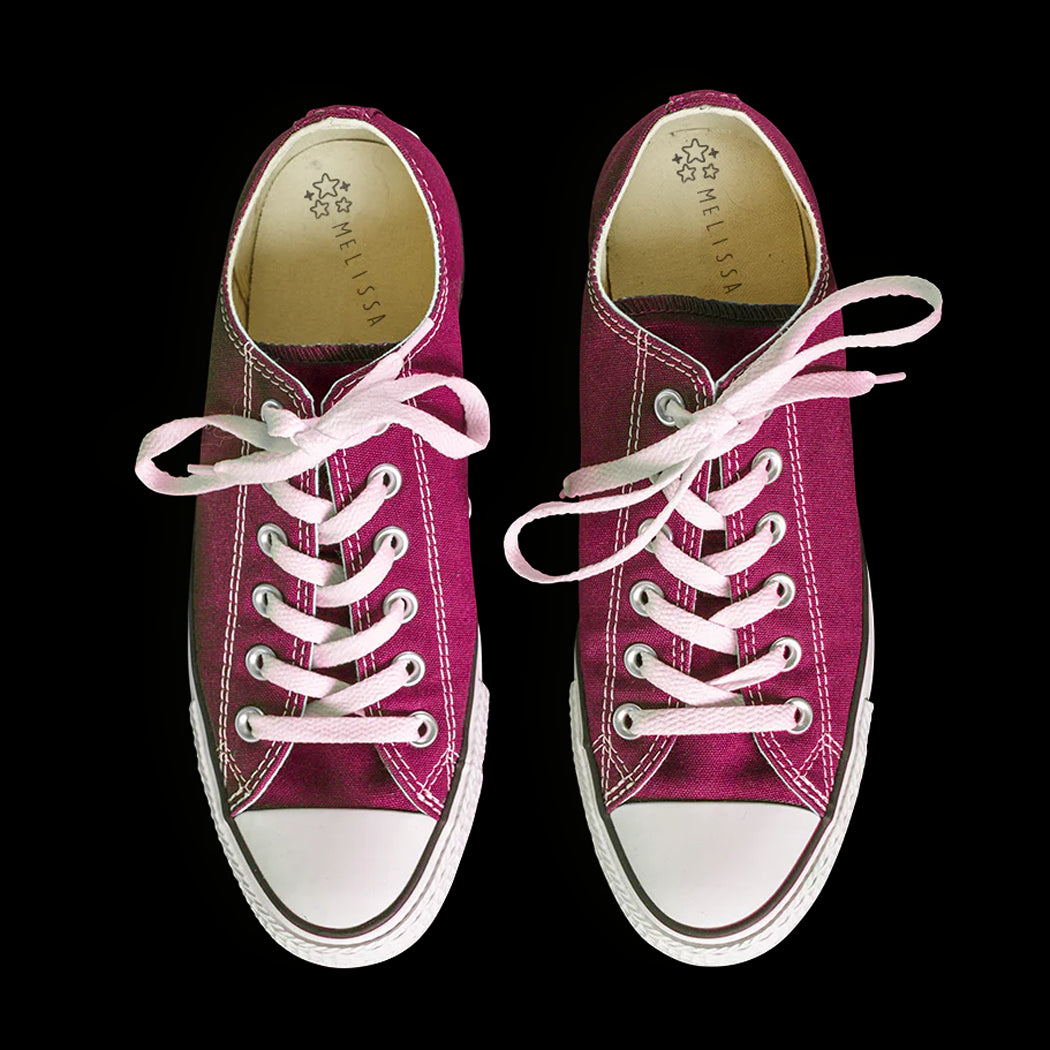 Pair of maroon sneakers with white laces on a black background