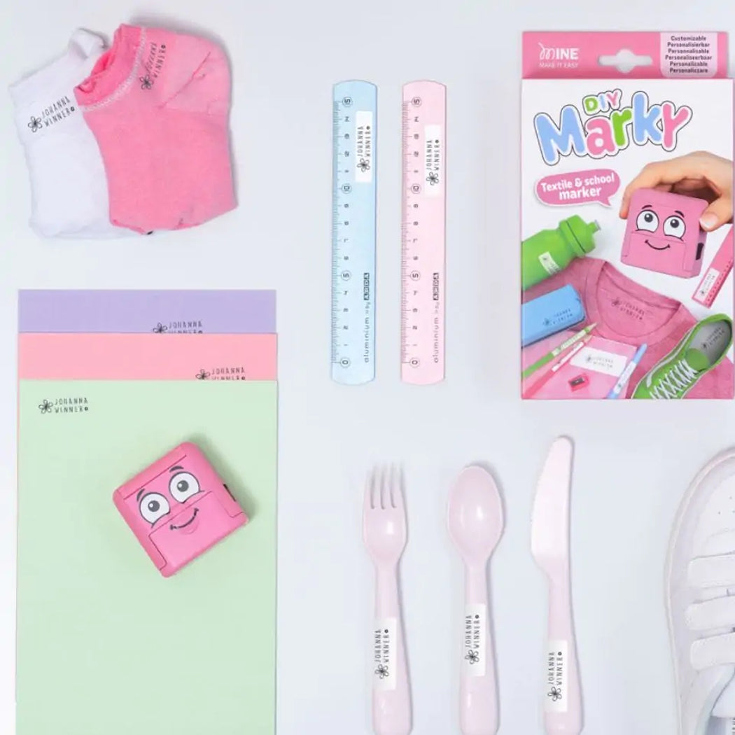 Collection of stationery items including pink markers, rulers, and cutlery on a white background.