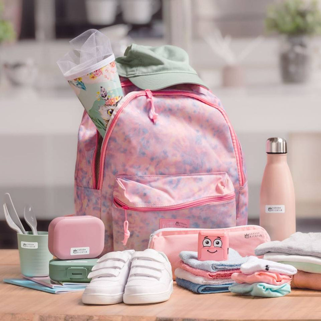 Pink backpack with baby care items on a wooden surface