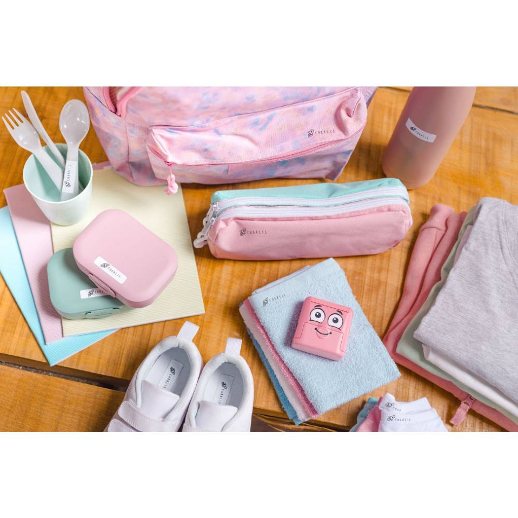 Collection of travel accessories including bags, pouches, and a small pouch with a face on a wooden surface.